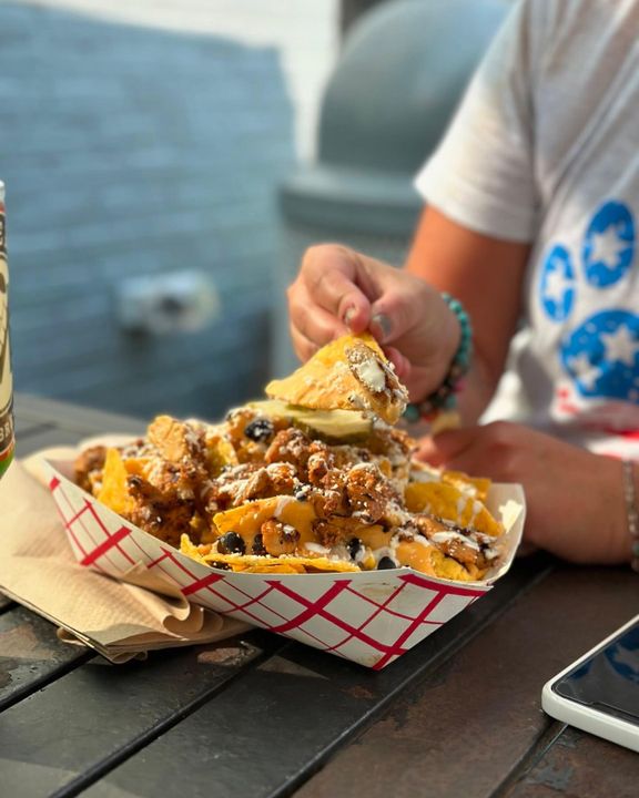 A loaded BLZN meal served in a basket at an outdoor table